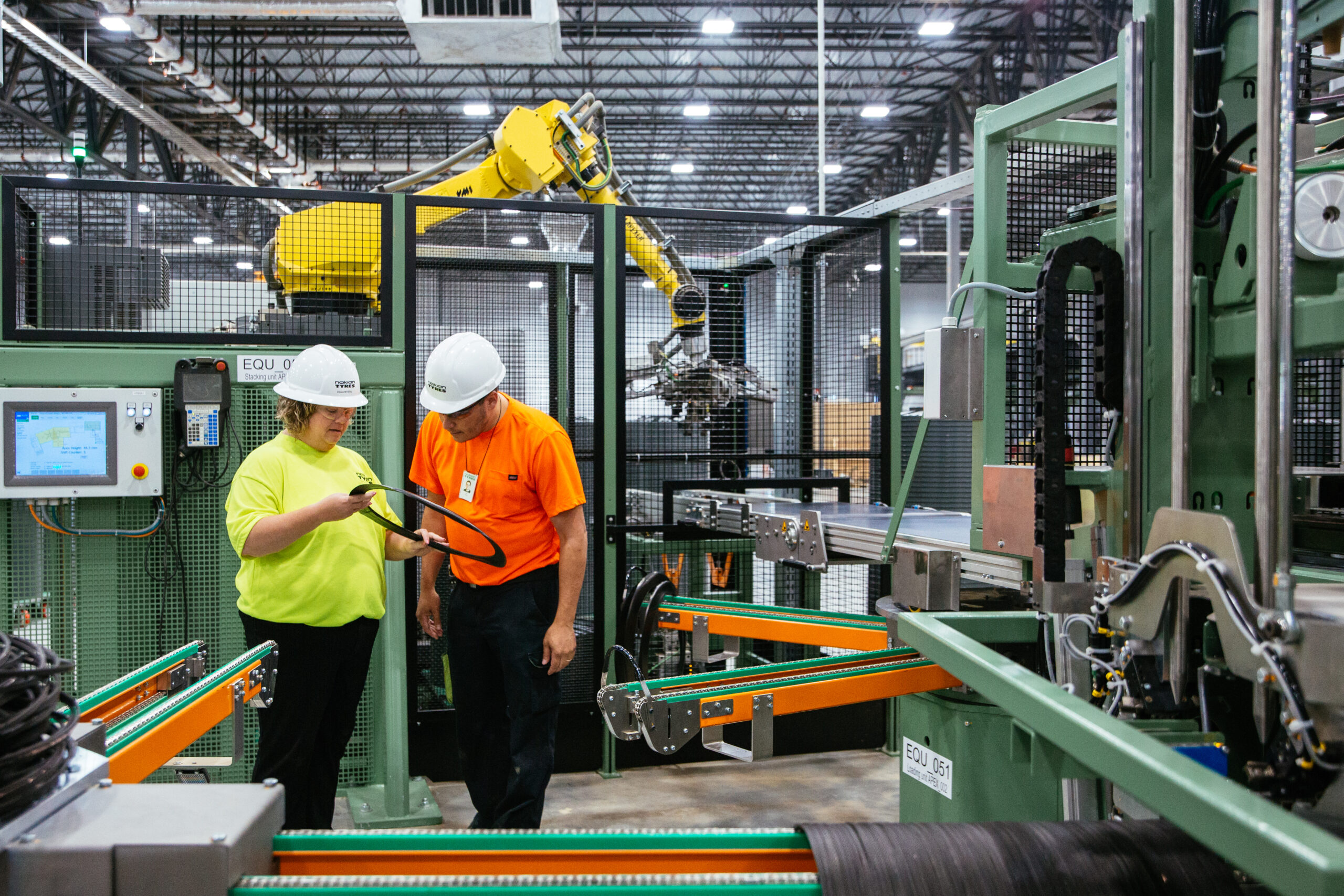 Man and woman inspect plastic ring in manufacturing setting